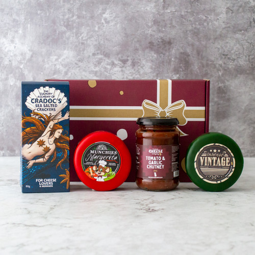 Grey background image of the Build Your Own Truckle Gift Box including two cheese truckles, a jar of chutney, and a box of crackers.